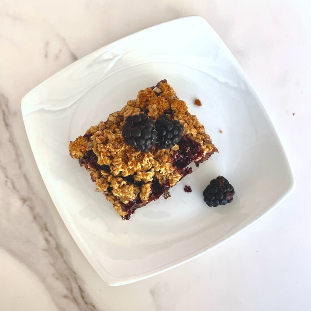 Gluten-Free Blackberry Crumble Protein Bar on a plate with fresh blackberries